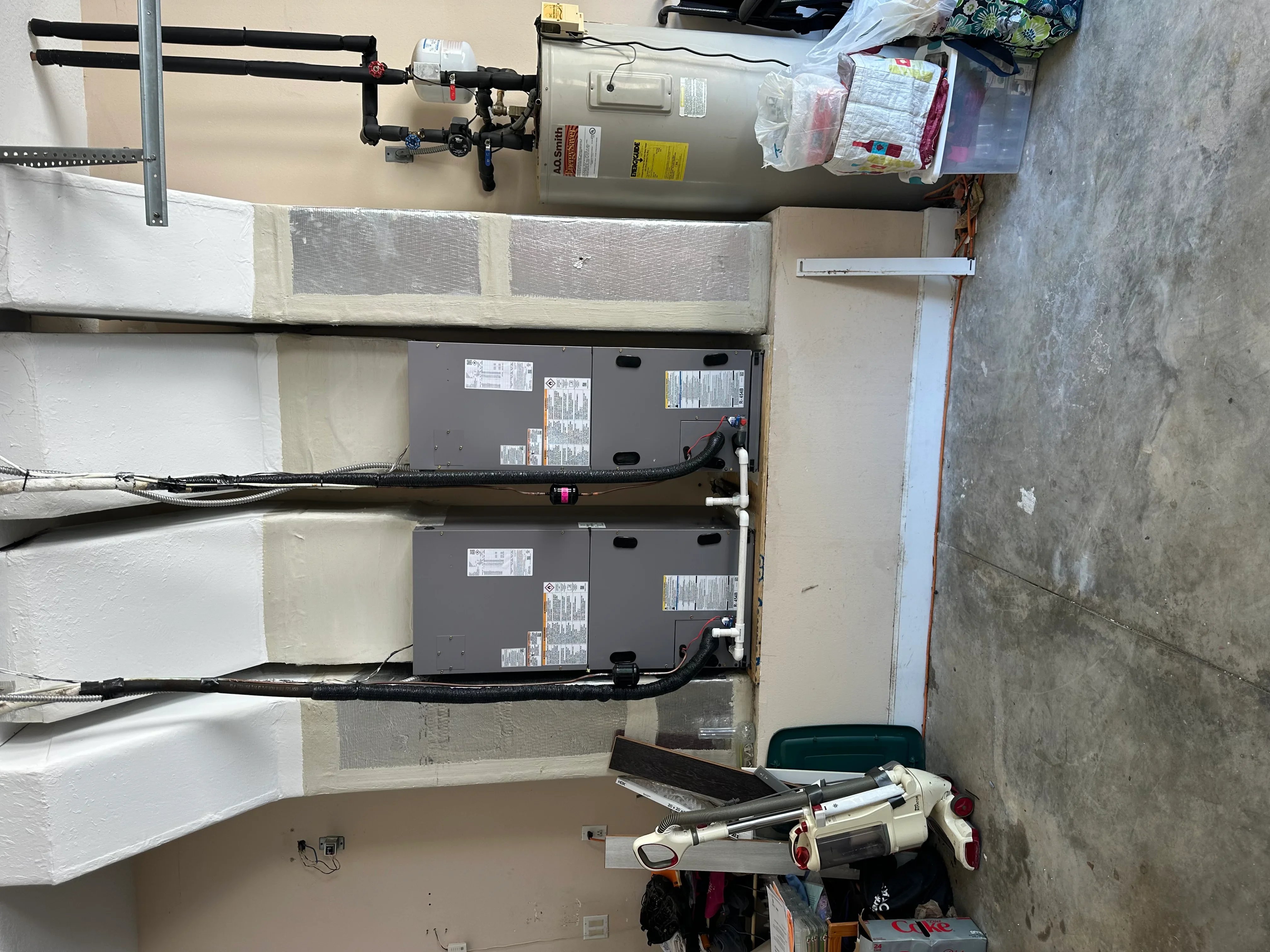 Dual water heater installation with black PVC piping and wall-mounted support system