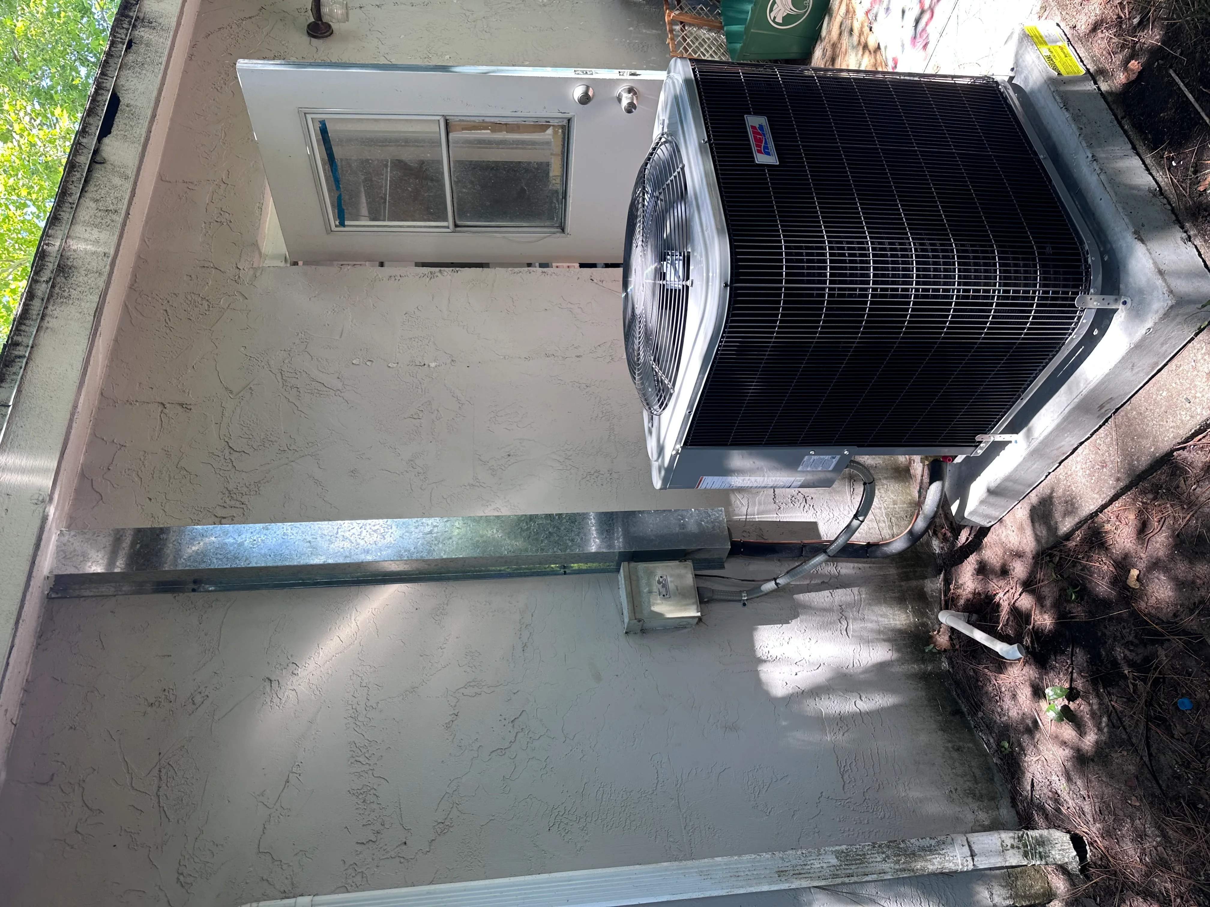 Newly installed outdoor AC condenser unit on concrete pad with electrical connections