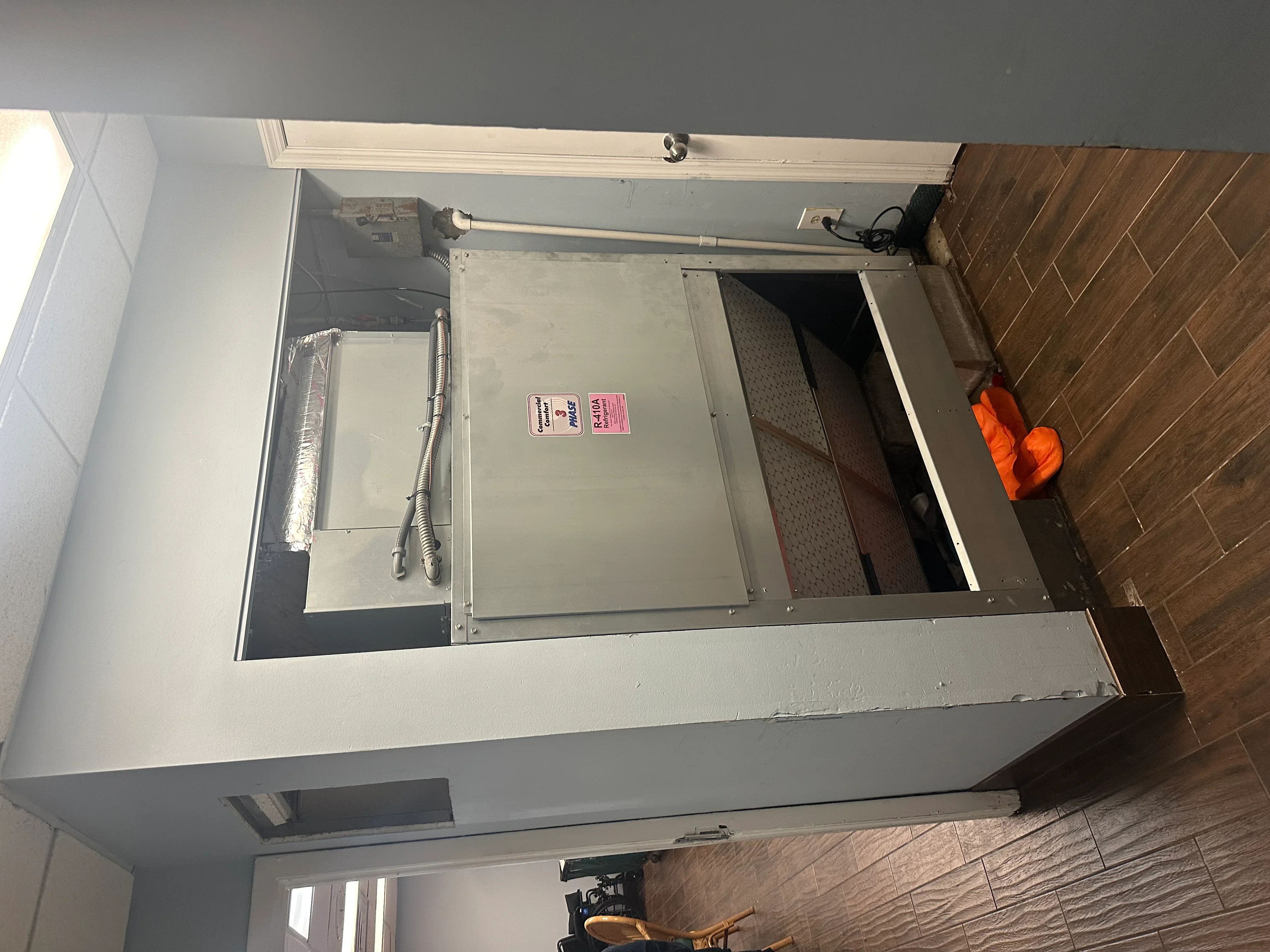 Ceiling-mounted HVAC unit with ductwork and electrical connections during installation