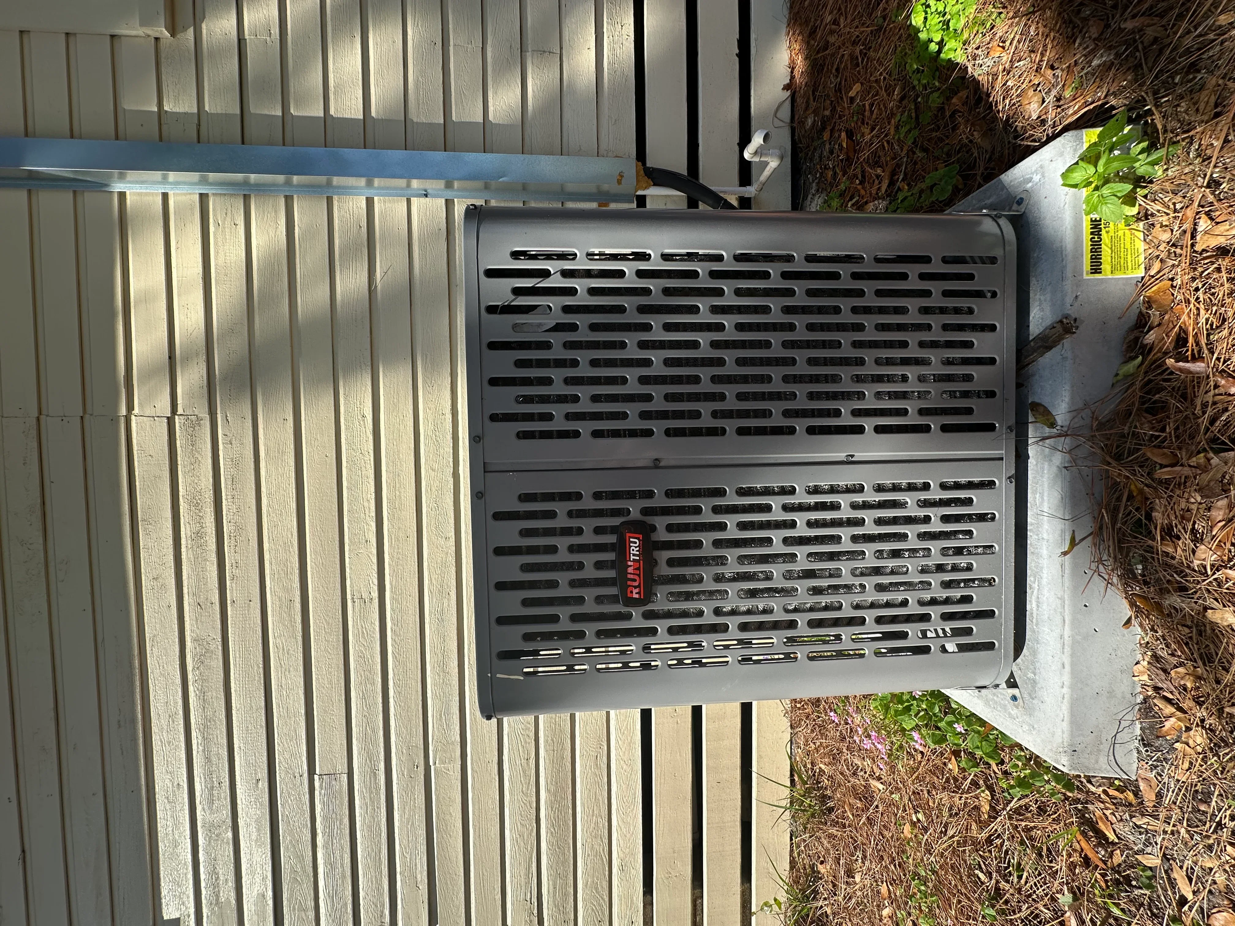Installed outdoor HVAC unit with metal housing and ventilation louvers on concrete pad