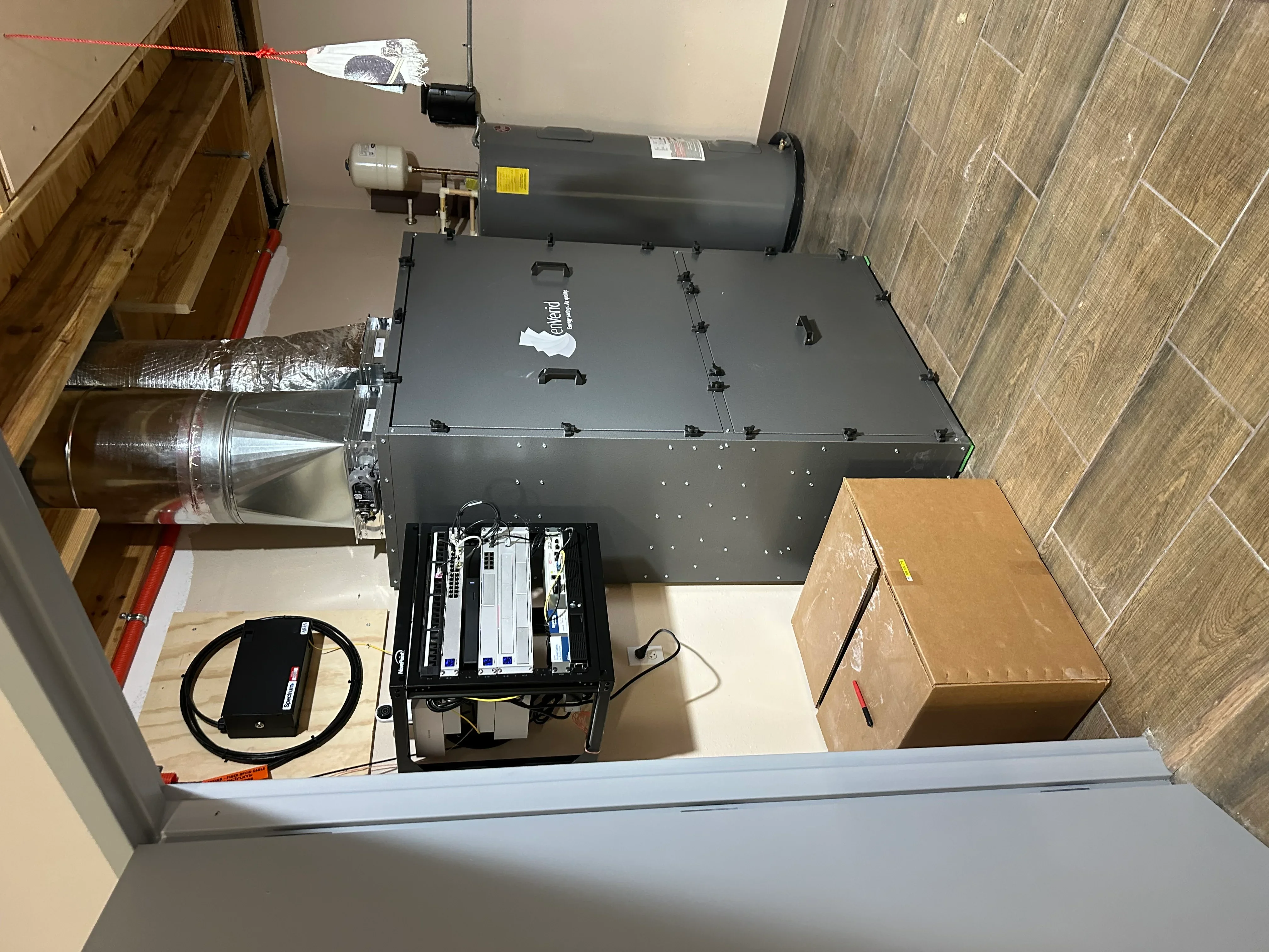 Installed gas furnace with gray metal housing, ductwork, and electrical components in residential space